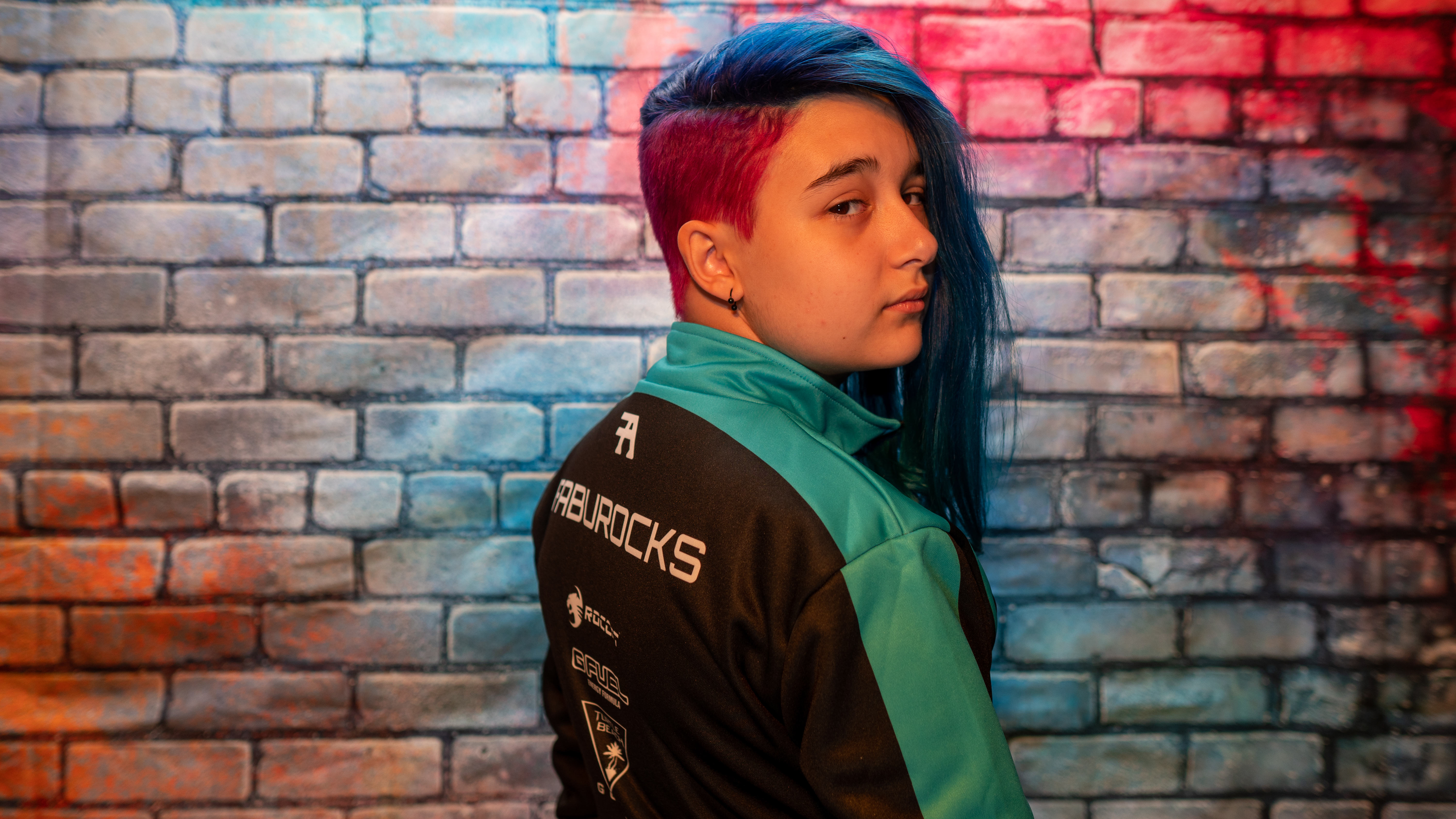 Fabu posing in a FabuRocks jacket in front of the brand portrait wall